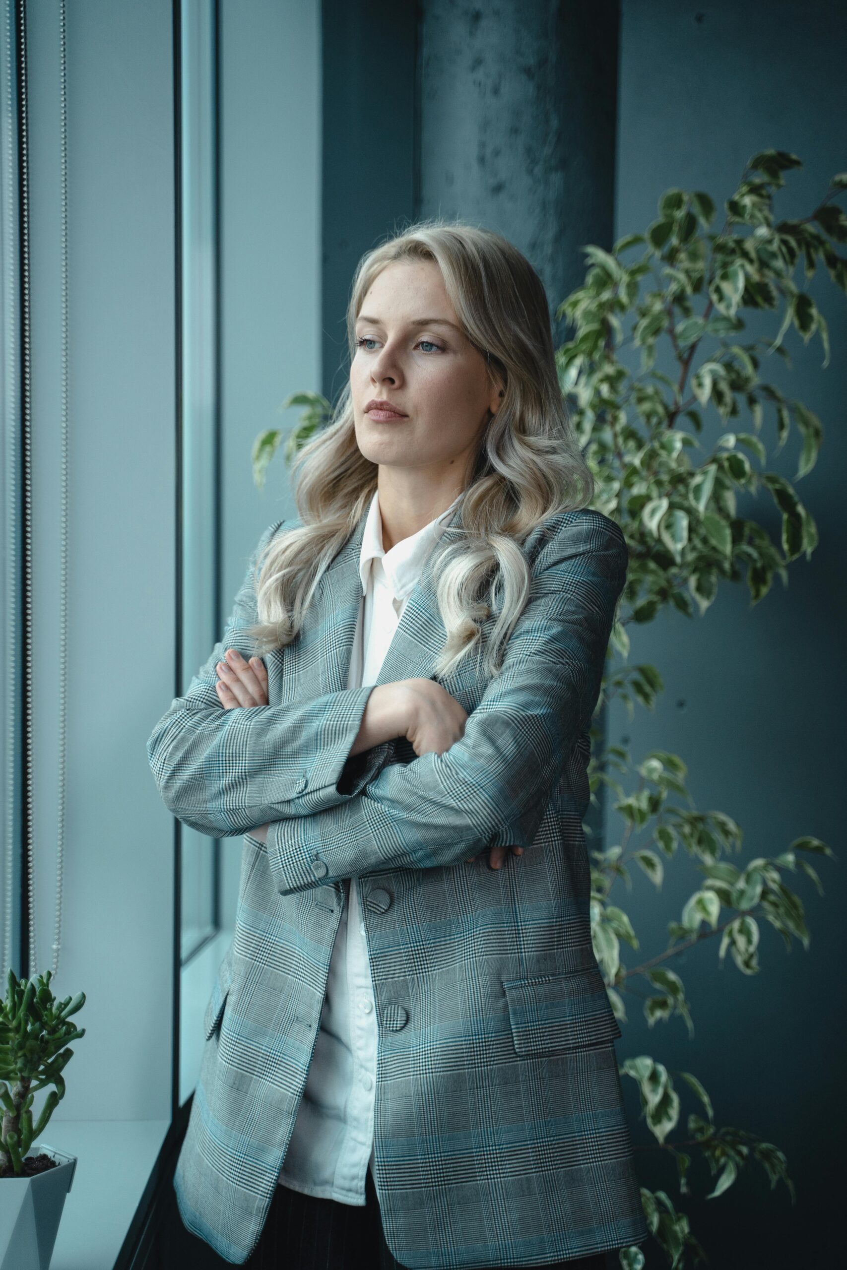 A poised female executive standing by a window, embodying leadership and professionalism.